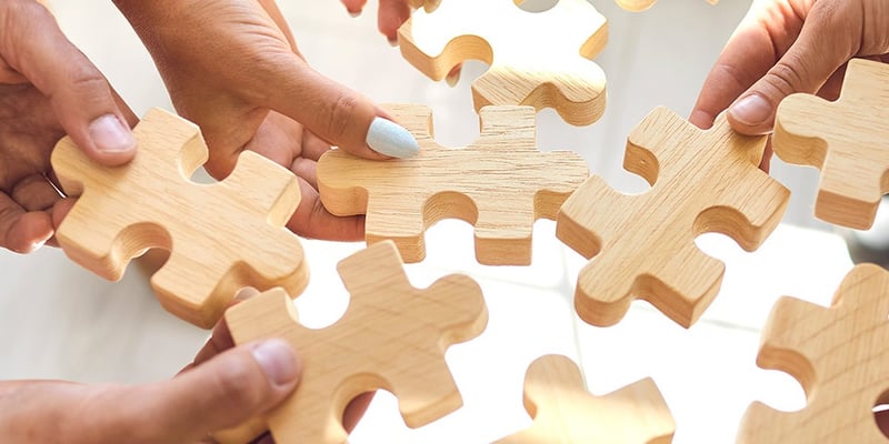 Symbolbild für Teamentwicklung: Mehrere Hände halten Puzzleteile zusammen